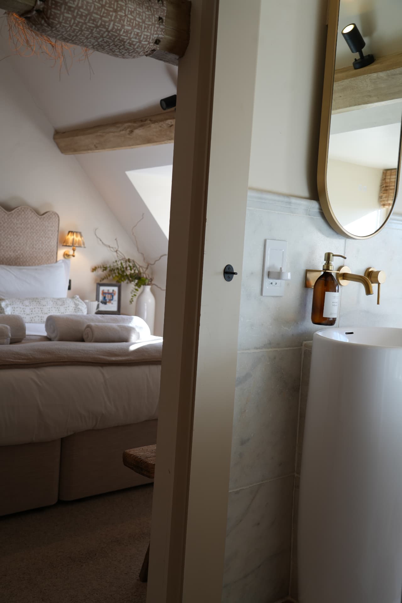 Basin and brass tap with the bed beyond the doorway