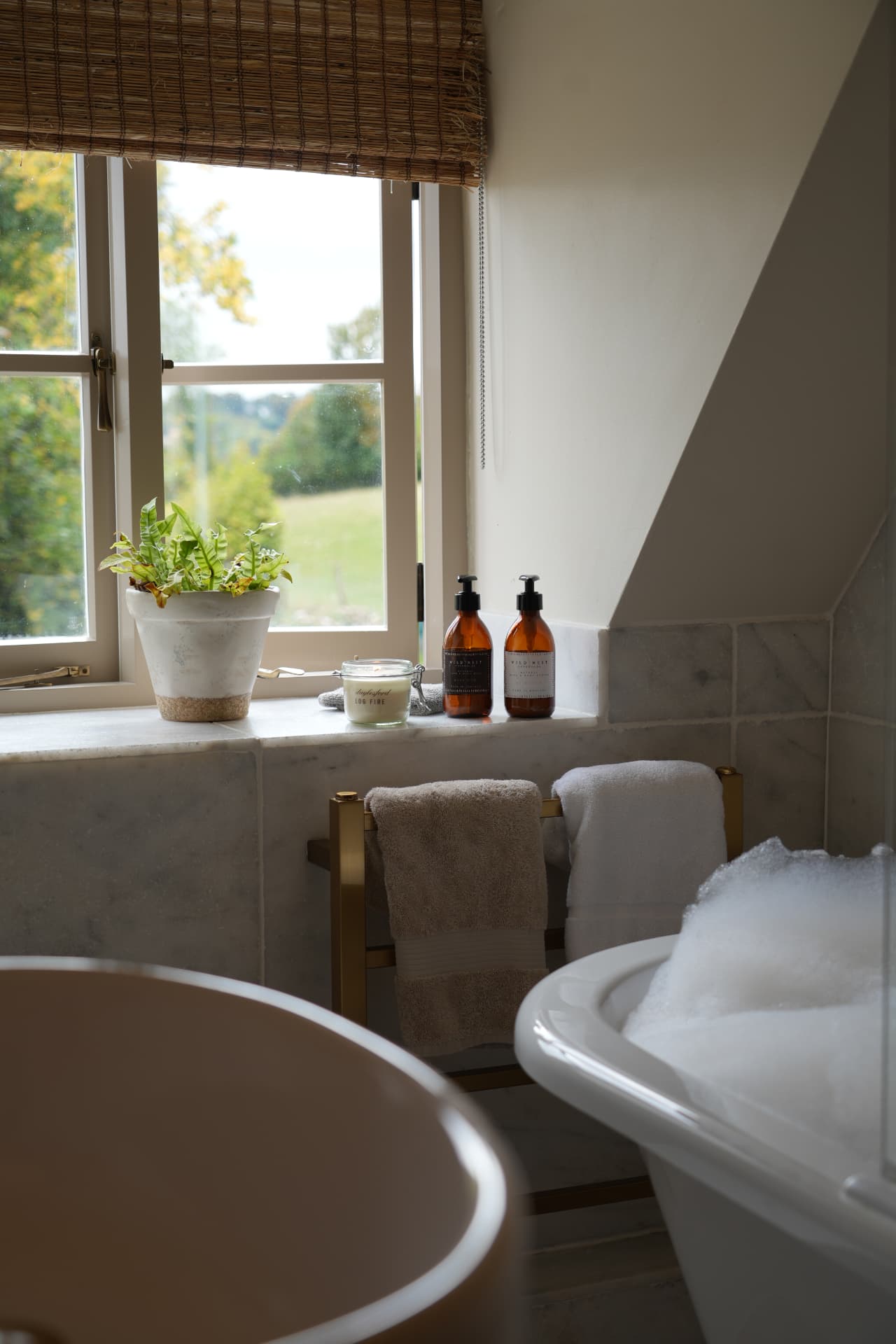 Roll-top bath beneath a window overlooking the hills