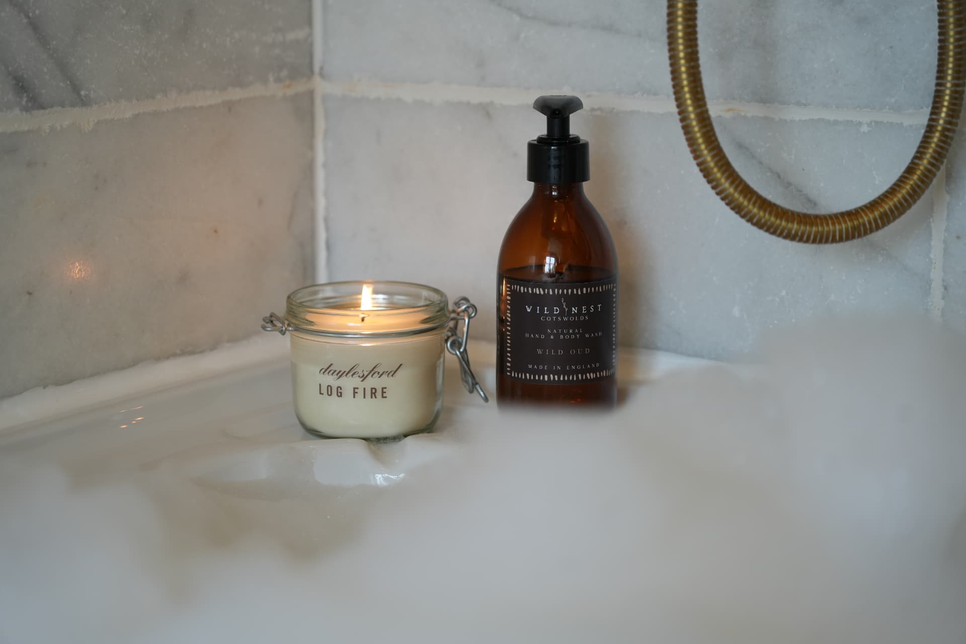 Lit candle resting in the foam of a marble bath