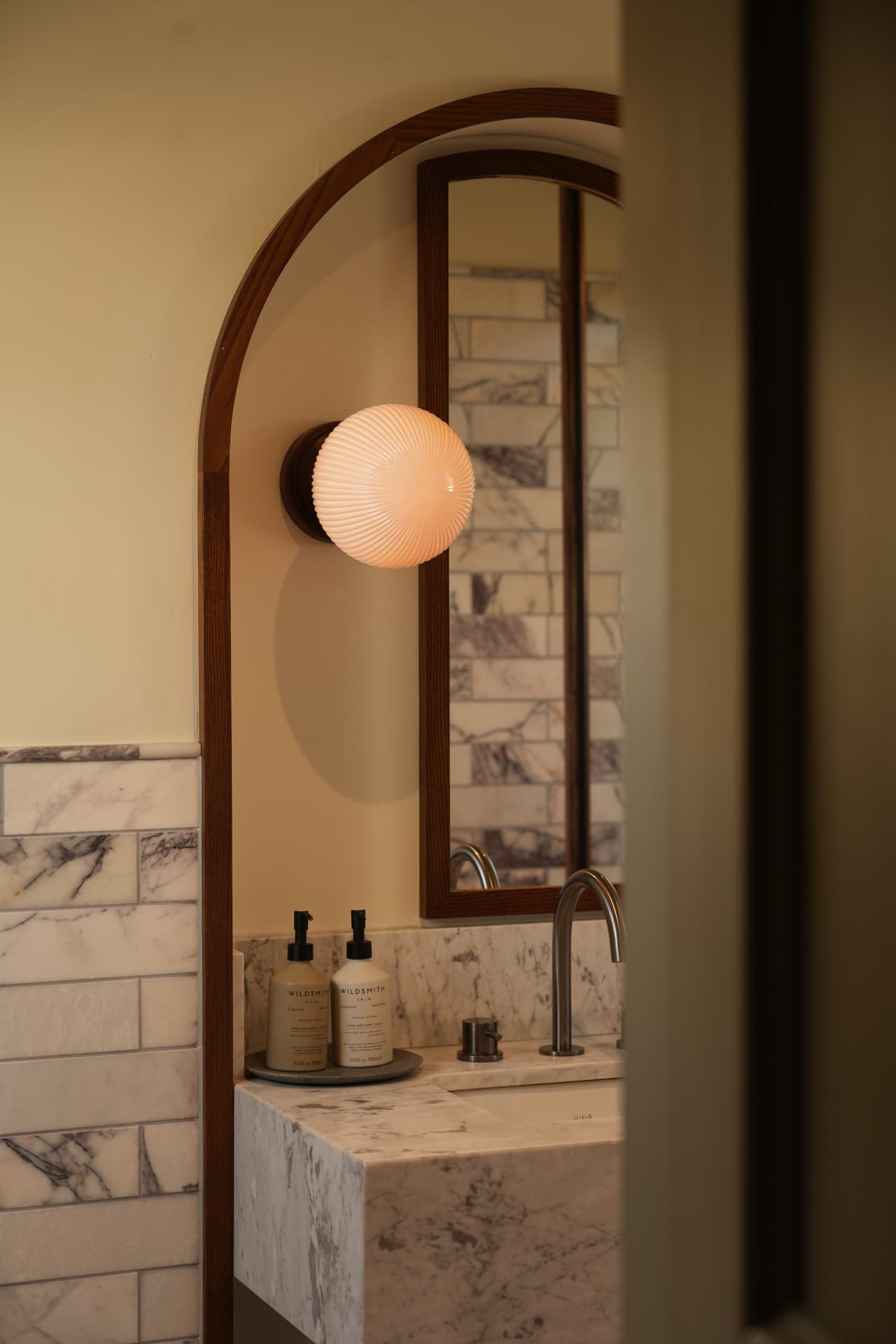 Marble bathroom vanity framed through an arched doorway